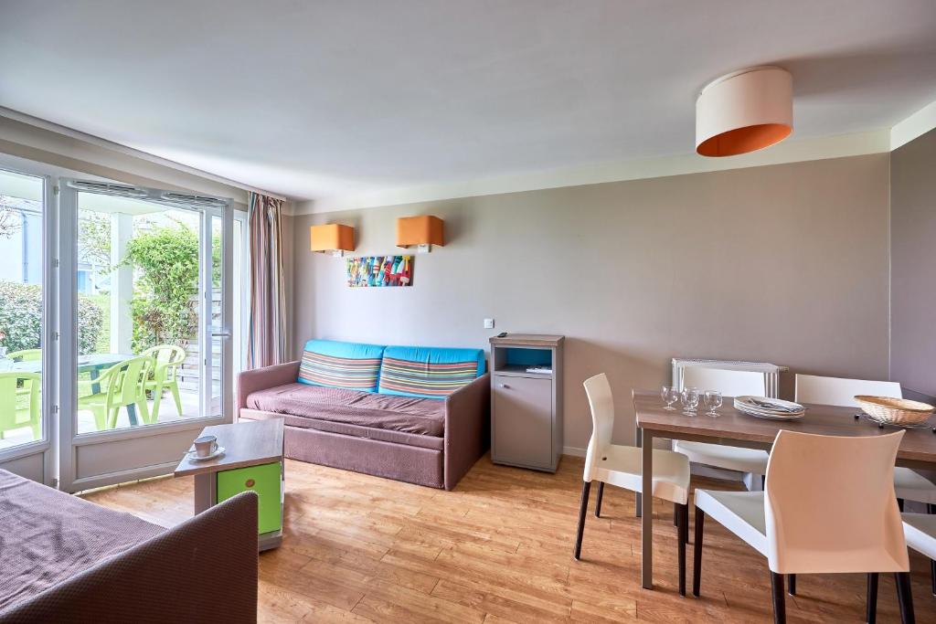 een woonkamer met een tafel en een bank bij L'Alouette - Appt en résidence avec terrasse in Courseulles-sur-Mer