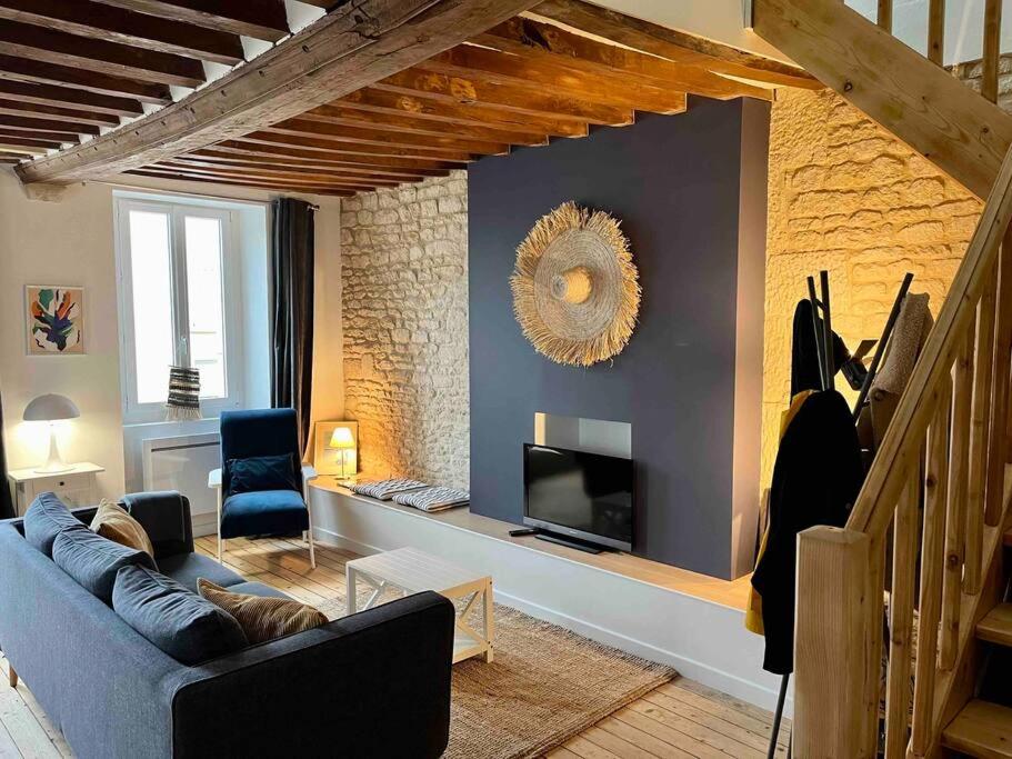 ein Wohnzimmer mit einem Sofa und einem TV in der Unterkunft La Petite Baleine, appt à 50m de la plage in Luc-sur-Mer