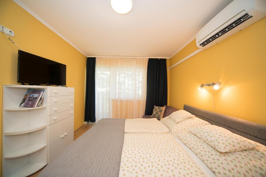 1 dormitorio con 1 cama, vestidor y TV en Siesta Vendégház, en Eger