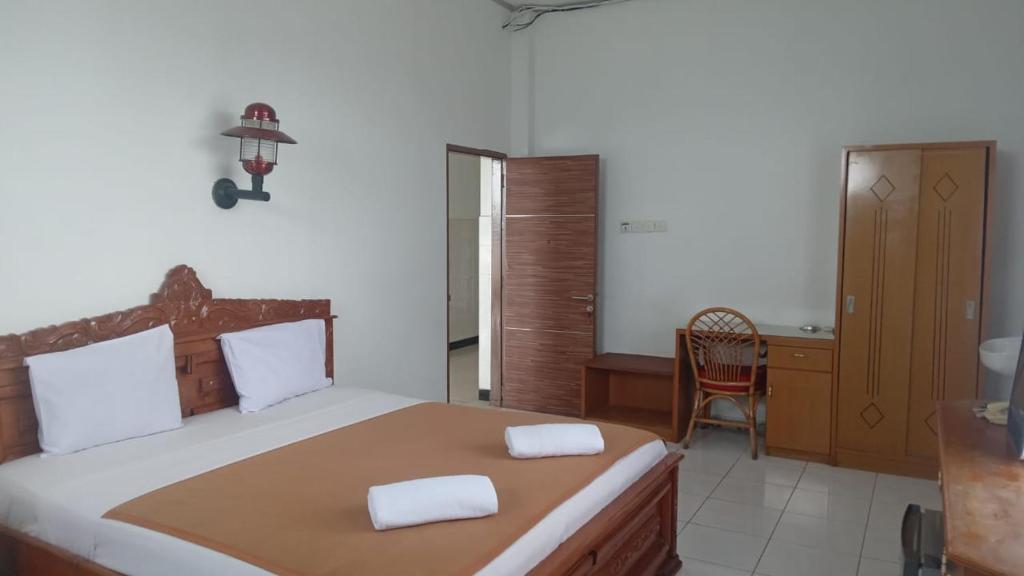 a bedroom with a bed with a desk and a chair at Hotel Asia Bukittinggi in Bukittinggi