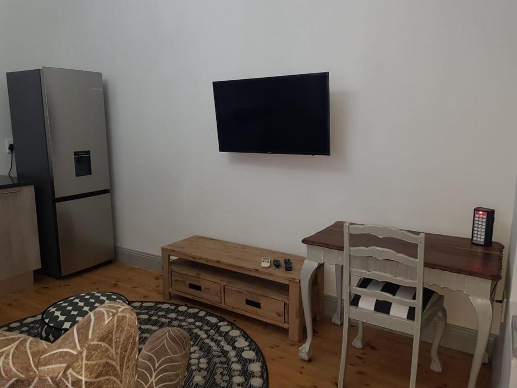 een woonkamer met een bureau en een televisie aan de muur bij Seba Cottages Mokopane in Mokopane