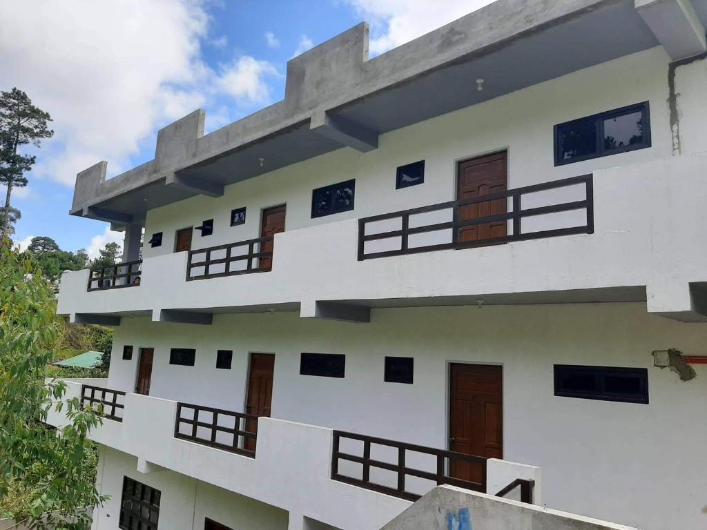 - un bâtiment blanc avec des portes et des fenêtres en bois dans l'établissement Baguio La Famille Residences, à Baguio