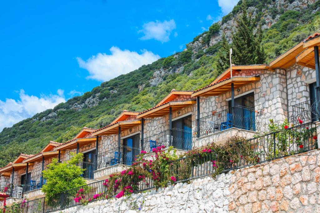 a building on a mountain with flowers at Kaş Köy Hotel in Kaş