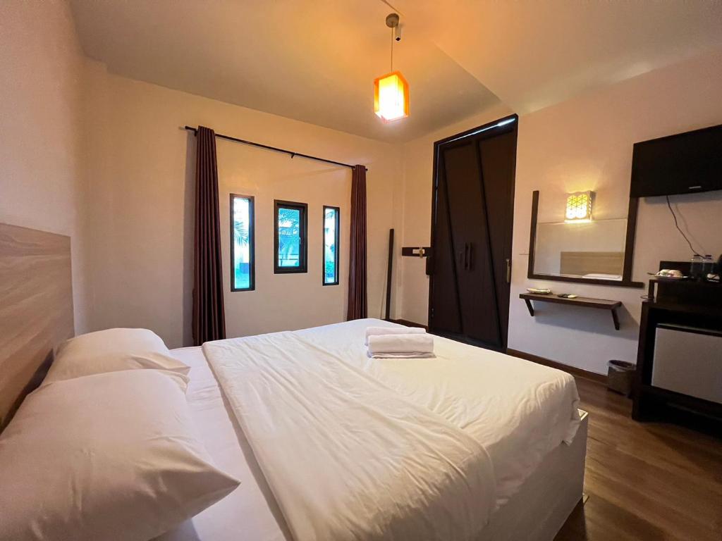 um quarto com uma cama branca e uma televisão em The Green Season Resort em Ban Mae Kham Lang Wat