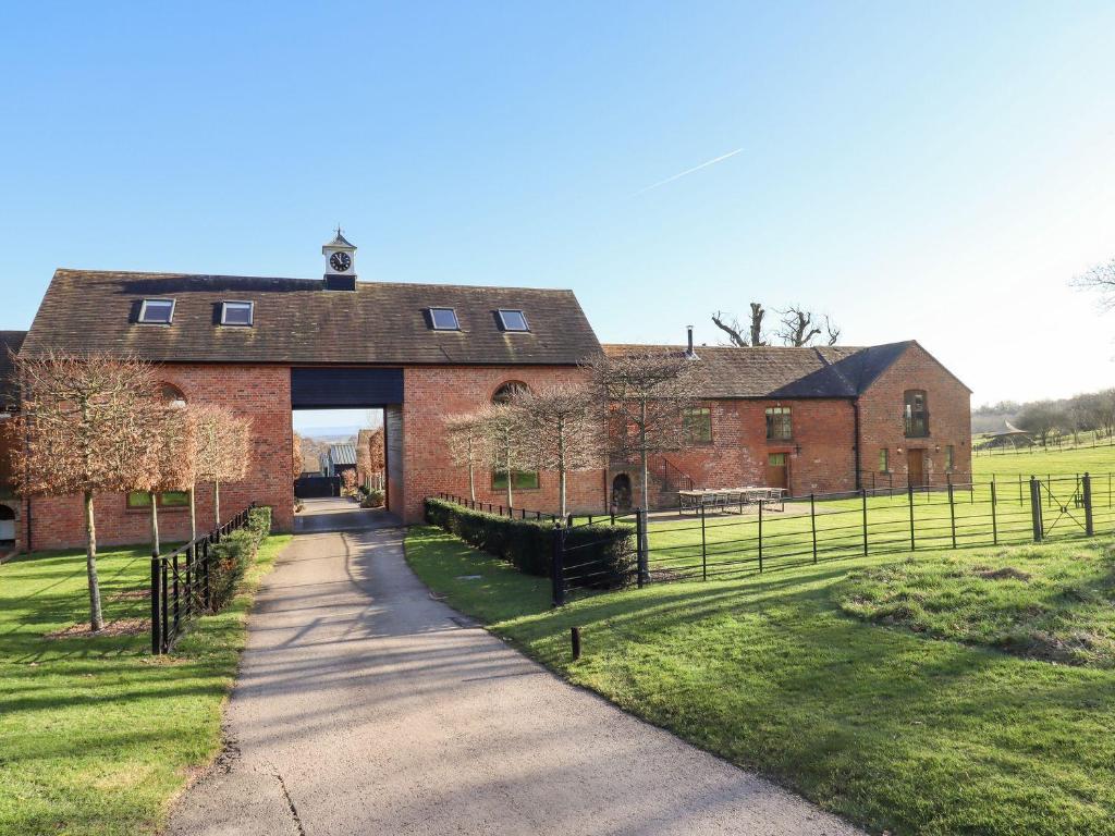 a large brick building with a gate in a field at The Carthouse in Ledbury