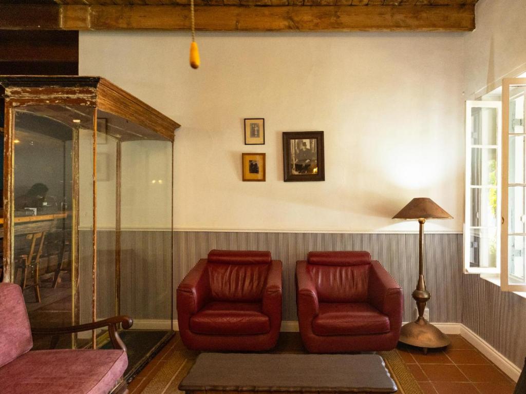 salon z 2 czerwonymi krzesłami i lampą w obiekcie Klaarstroom Hotel w mieście Klaarstroom