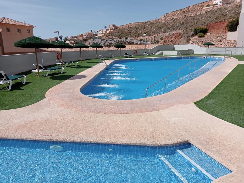 uma grande piscina com guarda-sóis no topo de um edifício em Apartamento Residencial Colinas del Golf, Envía, Almería em La Envia