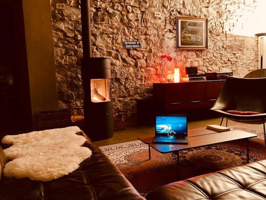 a living room with a couch and a laptop on a table at gerestaureerde hoeve met zicht in Durbuy