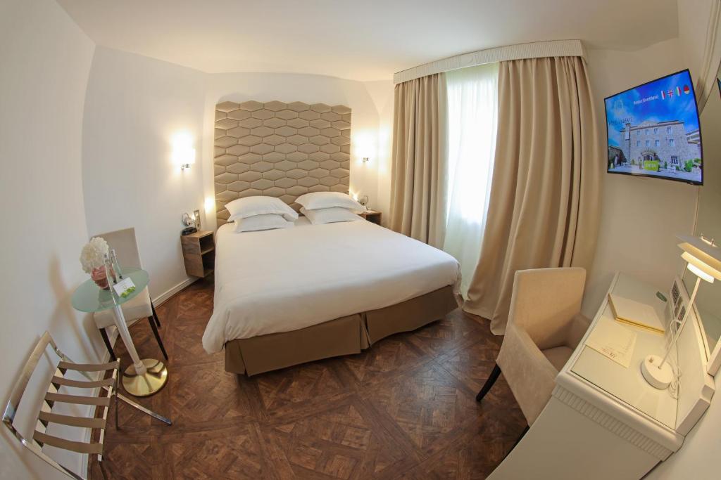a hotel room with a large bed and a staircase at Hôtel L'Abbaye in Calvi