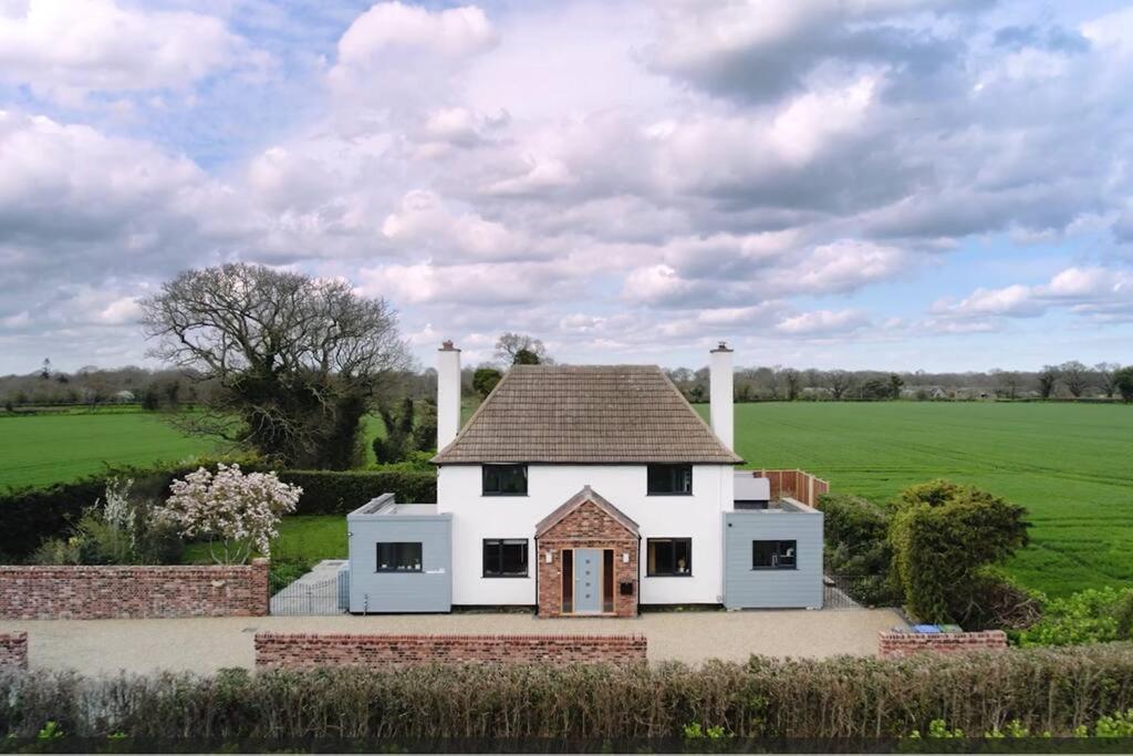 a white house with a roof on a field at Covehithe House-Coastal luxury- sleeps 12-with huge swimspa! in Wrentham