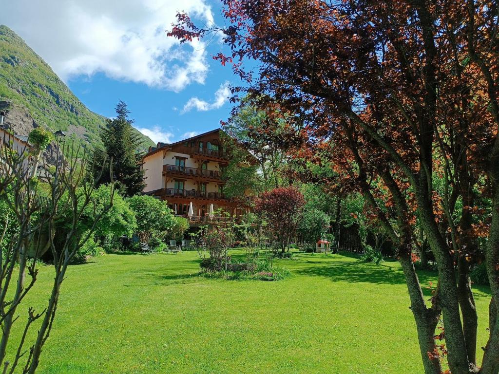 um pátio verde com um edifício ao fundo em Hotel Estanys Blaus em Tavascan