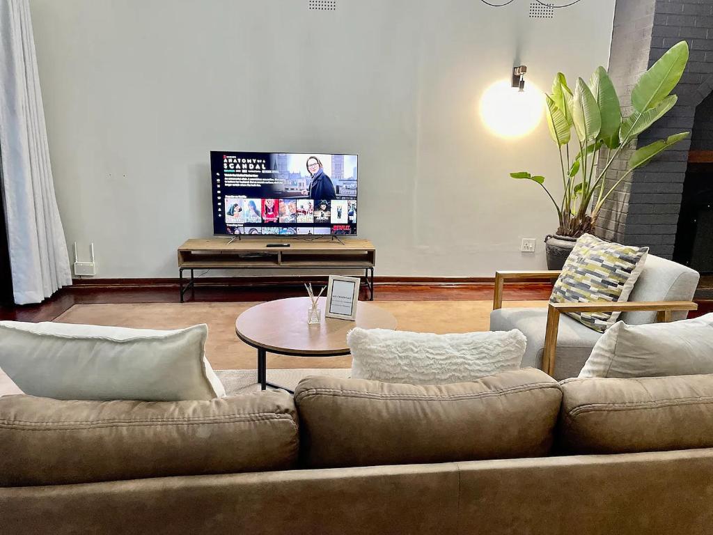 a living room with a couch and a tv at Cozy 3 Bedroom House with unique bathrooms - 2084 in Bulawayo