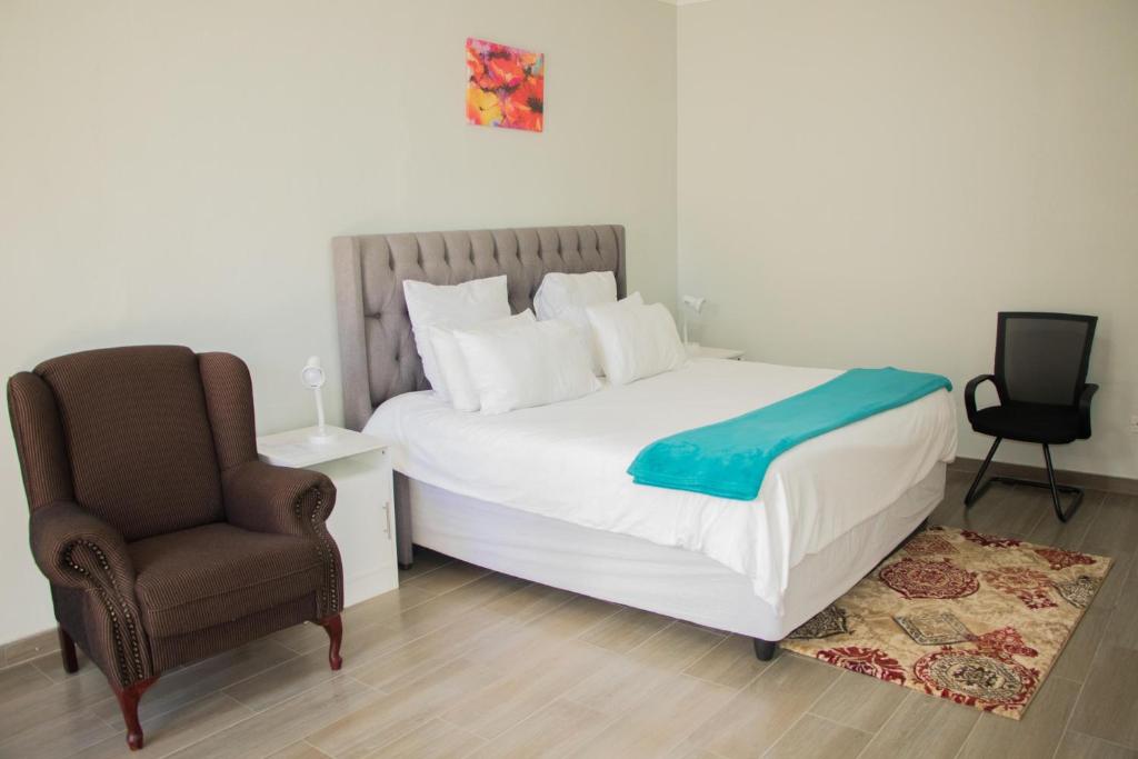 a bedroom with a bed and a chair at Standard room in Morningside guesthouse - 2090 in Bulawayo