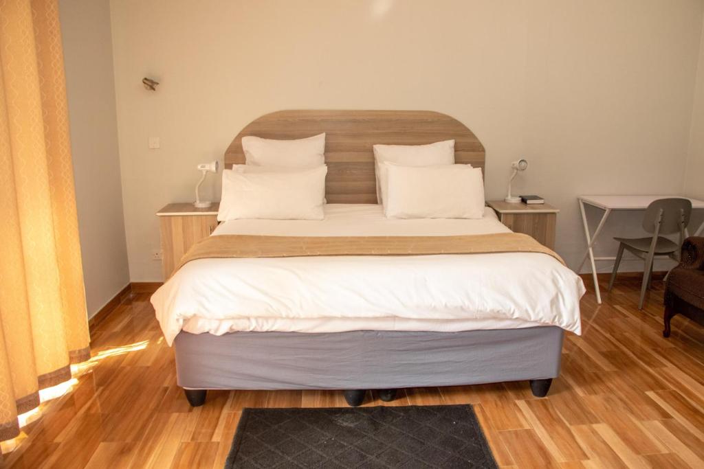 um quarto com uma cama grande com lençóis brancos e almofadas em Neat one bedroom in Morningside guesthouse - 2091 em Bulawayo