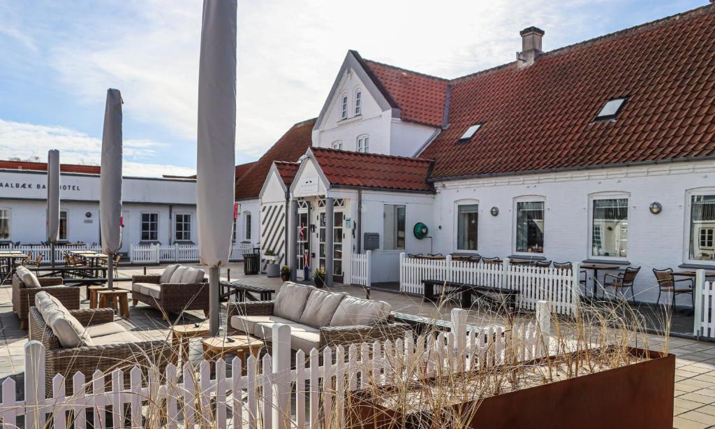 um edifício com uma cerca branca, cadeiras e mesas em Aalbæk Badehotel em Ålbæk