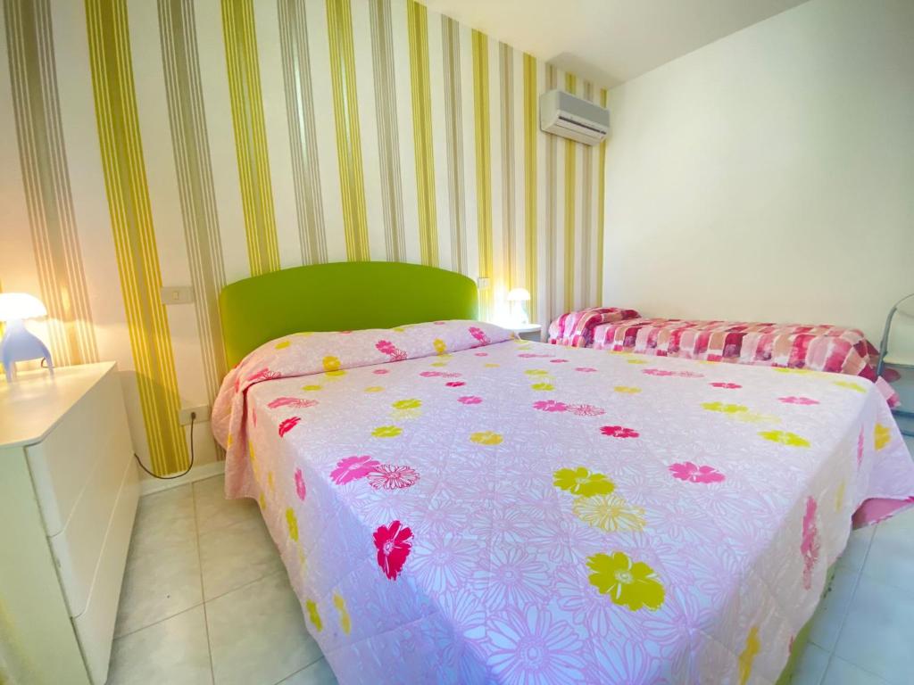 1 dormitorio con 1 cama con edredón rosa y amarillo en Venere Apartament, en Tirrenia