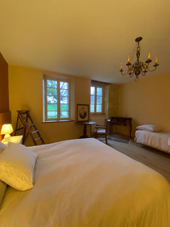 Un dormitorio con una gran cama blanca y una lámpara de araña. en Chambres d'hôtes de charme avec piscine - Le Clos Boissiere, en Valence-sur-Baïse