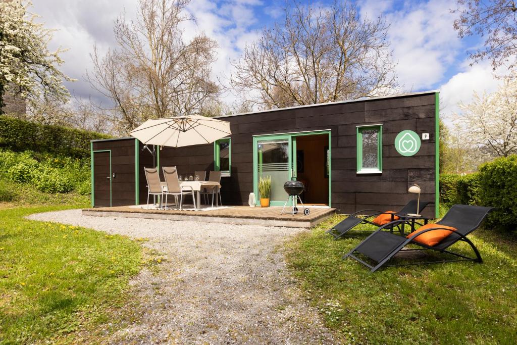 une petite maison noire avec un parapluie dans l'établissement Radapartment -Terrasse & Grill - by homekeepers, à Iphofen