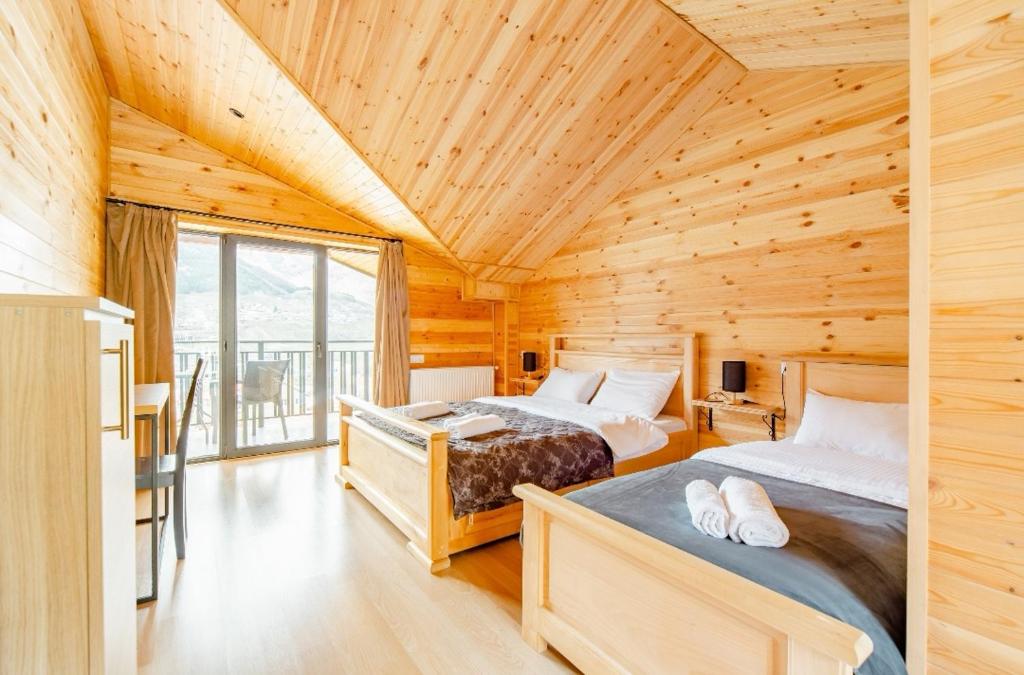 two beds in a room with wooden ceilings at Aronia Kazbegi in Stepantsminda