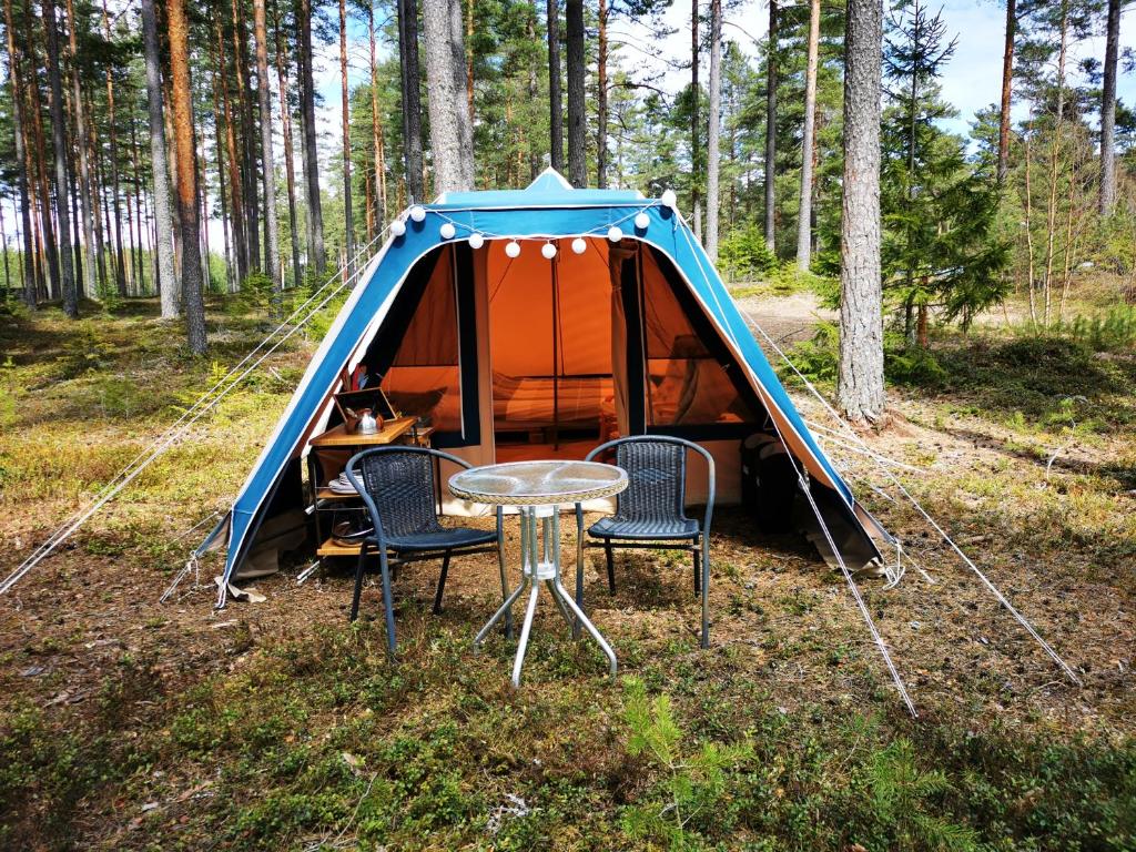 a tent with chairs and a table in the woods at Volledig ingerichte tent op natuurcamping in Gräsmark