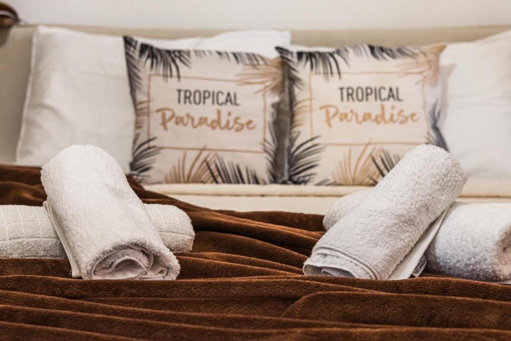 una pila de toallas en una cama con almohadas en Loutraki Beach & Casino Condo en Loutraki