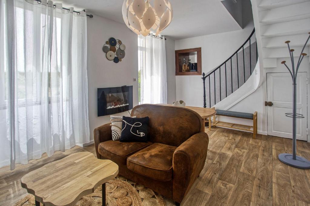 ein Wohnzimmer mit einem Ledersessel und einem Tisch in der Unterkunft Le Grand Fief - Appt pour 4 voyageurs in Bourg-Charente