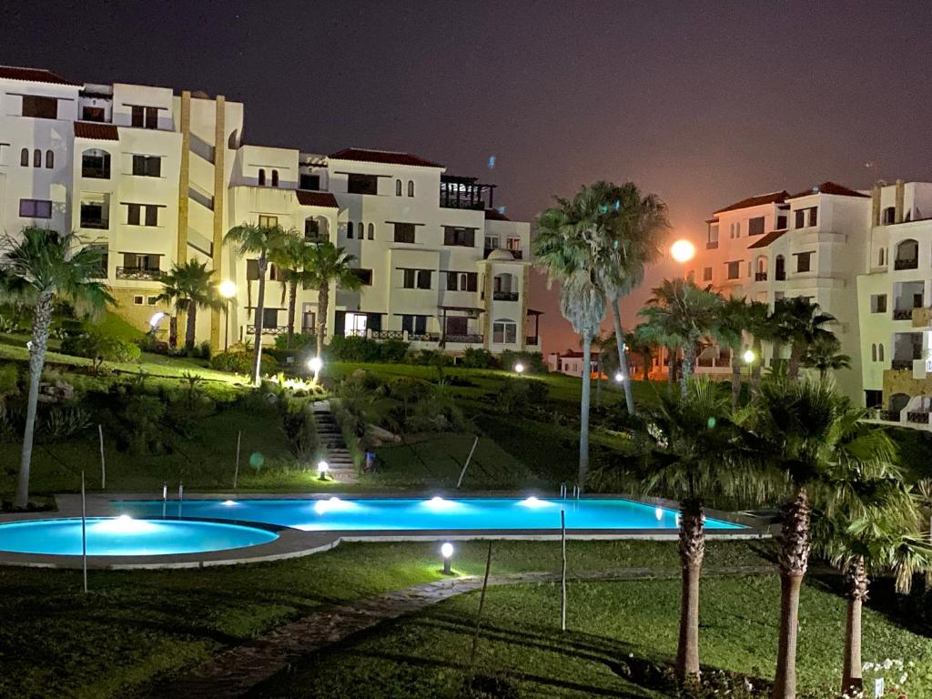 a swimming pool in front of a building at night at CABO NEGRO - LILAC'S GARDEN - PISCINE - JARDIN - PARKING in Martil