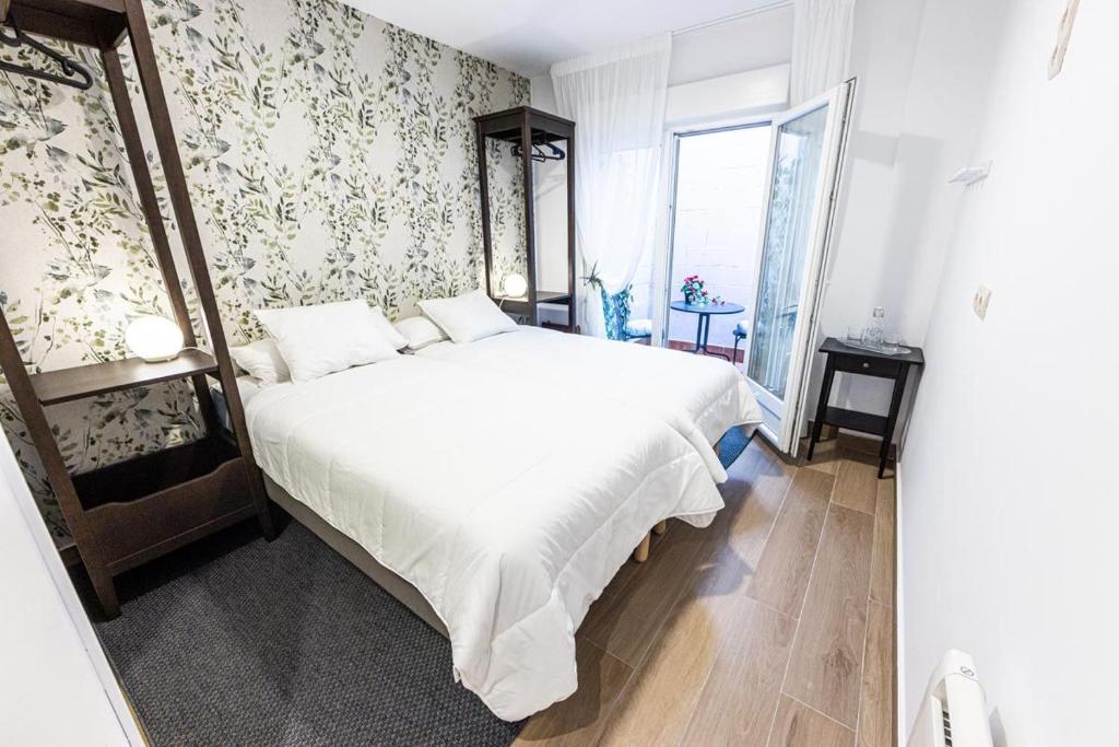 a bedroom with a large white bed with floral wallpaper at Hospedaxe Memorias de Sophia in Fisterra