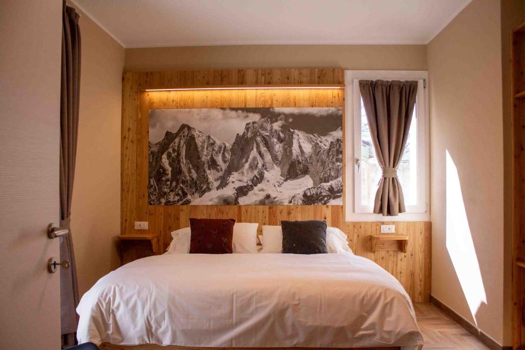 1 dormitorio con 1 cama con una pintura en la pared en Garni Le Grigne en Barzio