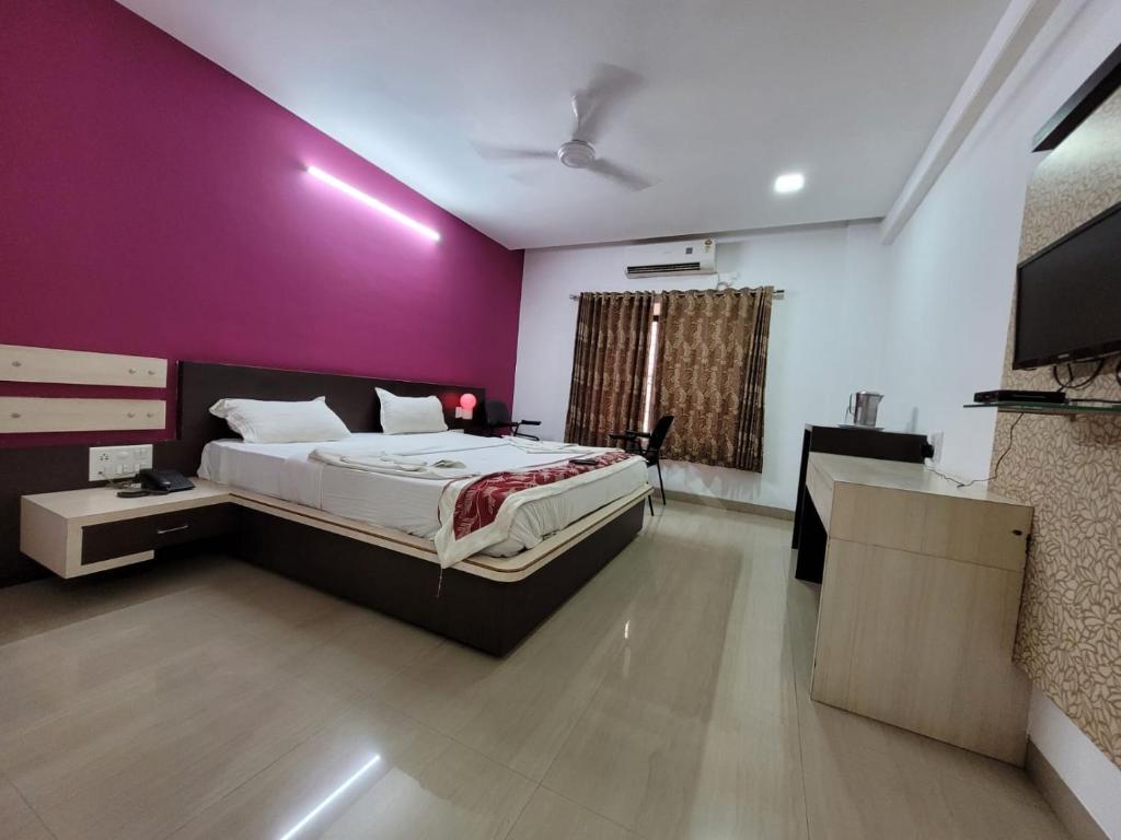 a bedroom with a bed and a purple wall at Sandesh Resort in Wai