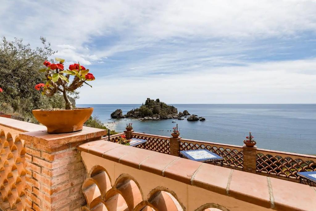 a vase of flowers on a brick wall with the ocean at Isola Bella - Rooms il Pescatore in Taormina