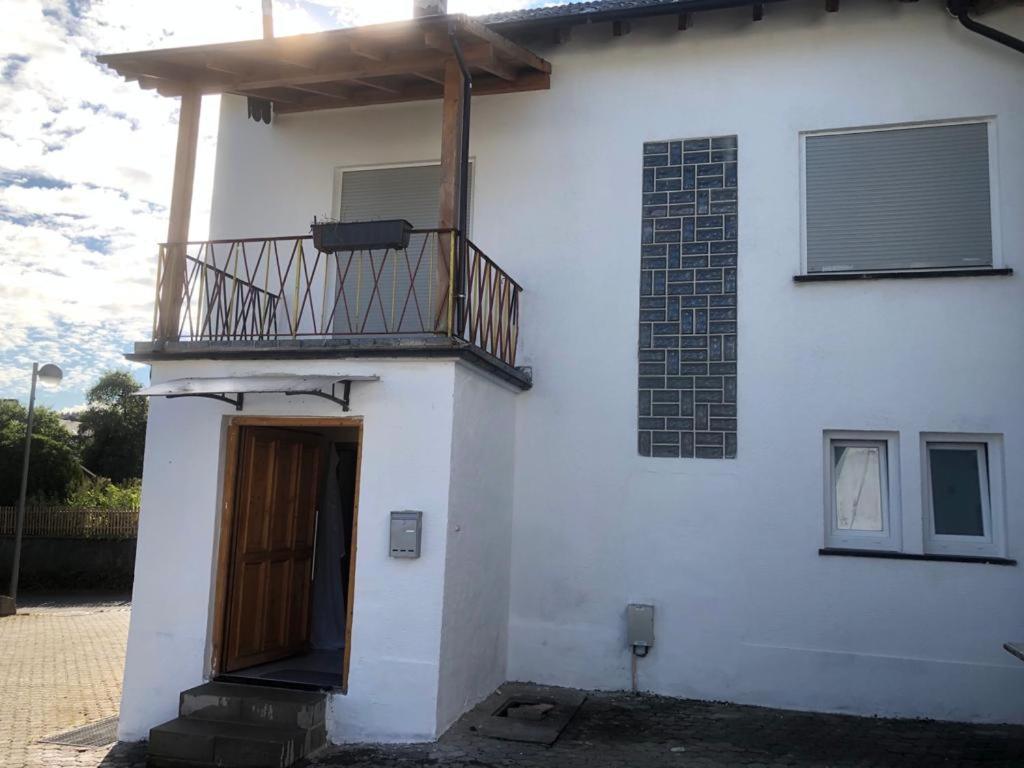 a white house with a balcony on top of it at Sinan's Bio Tourismus Farm Appartement in Betteldorf