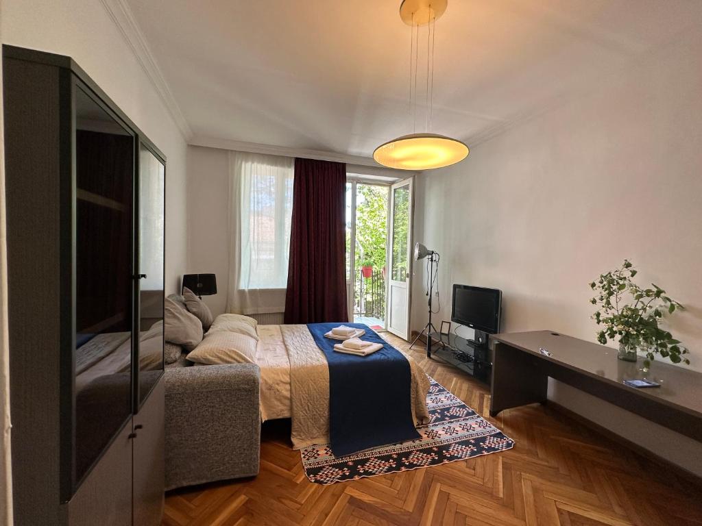 1 dormitorio con 1 cama y TV en Cozy home office in Vake en Tiflis