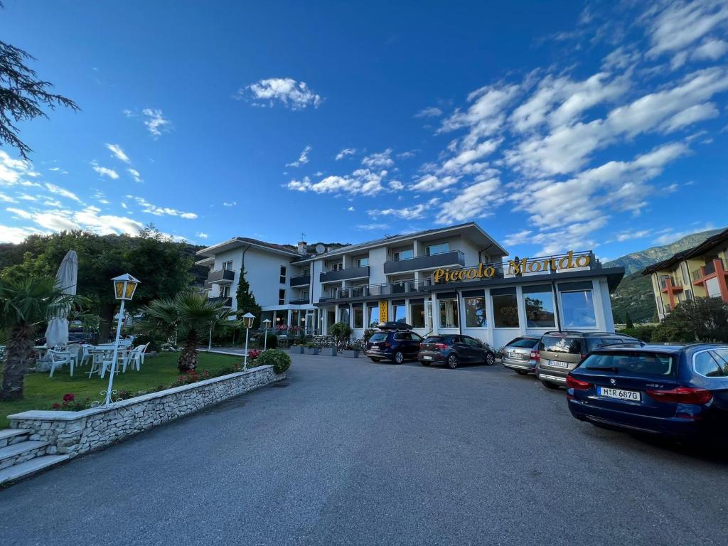 a hotel with cars parked in a parking lot at Hotel Piccolo Mondo in Nago-Torbole