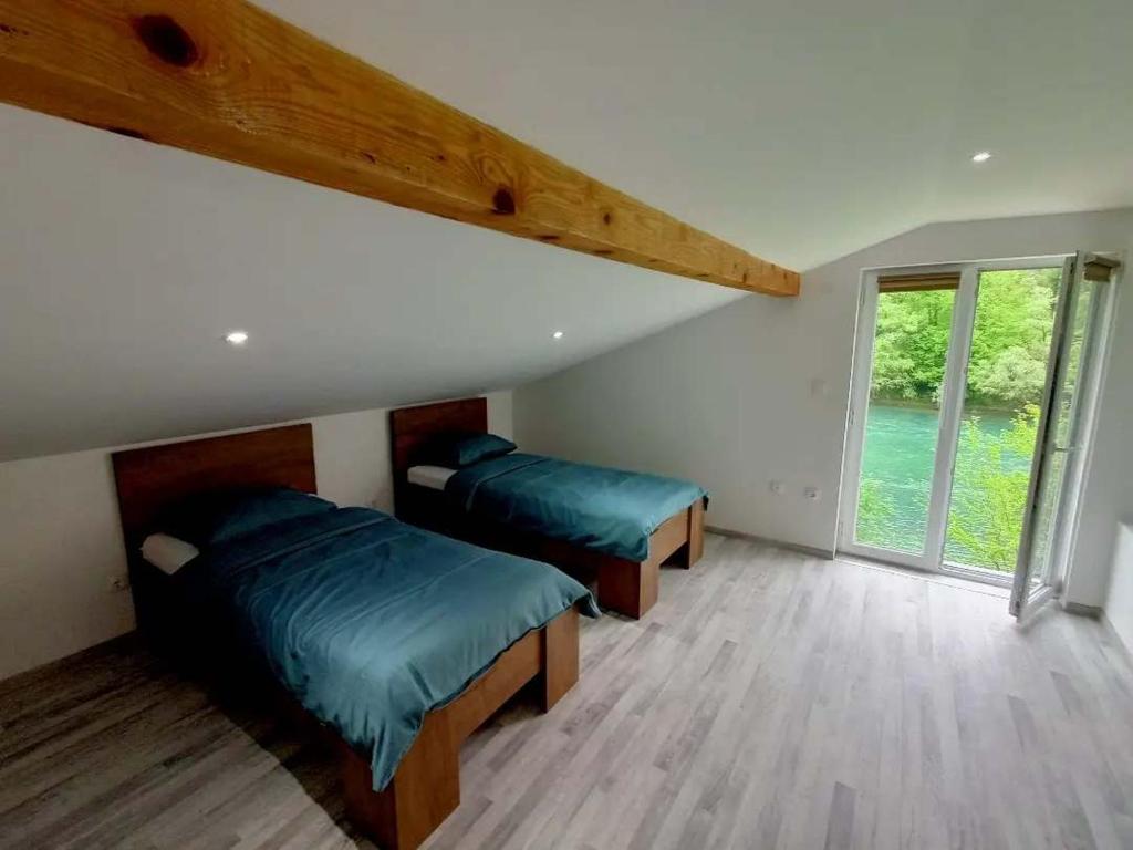 a bedroom with two beds and a large window at Anur Apartment in Bihać
