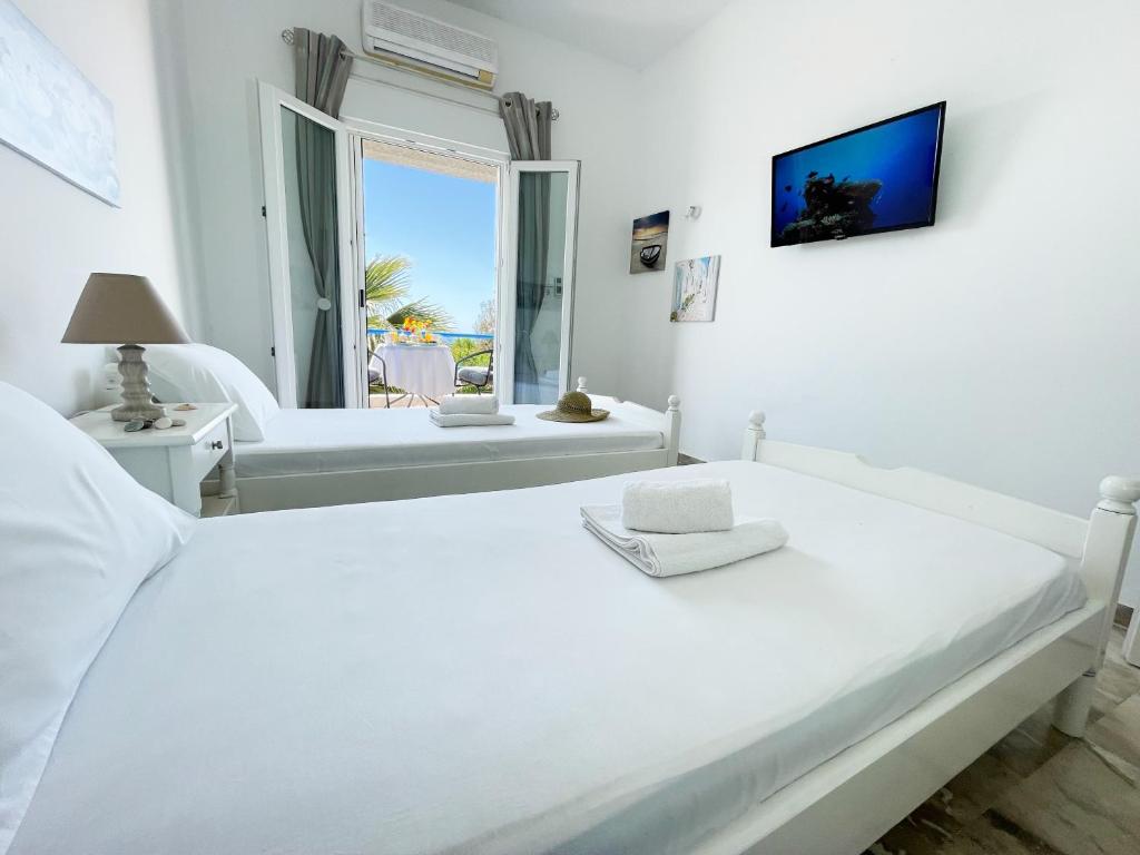 a white bedroom with a large white bed and a window at Odysseas Apartments in Marathokampos