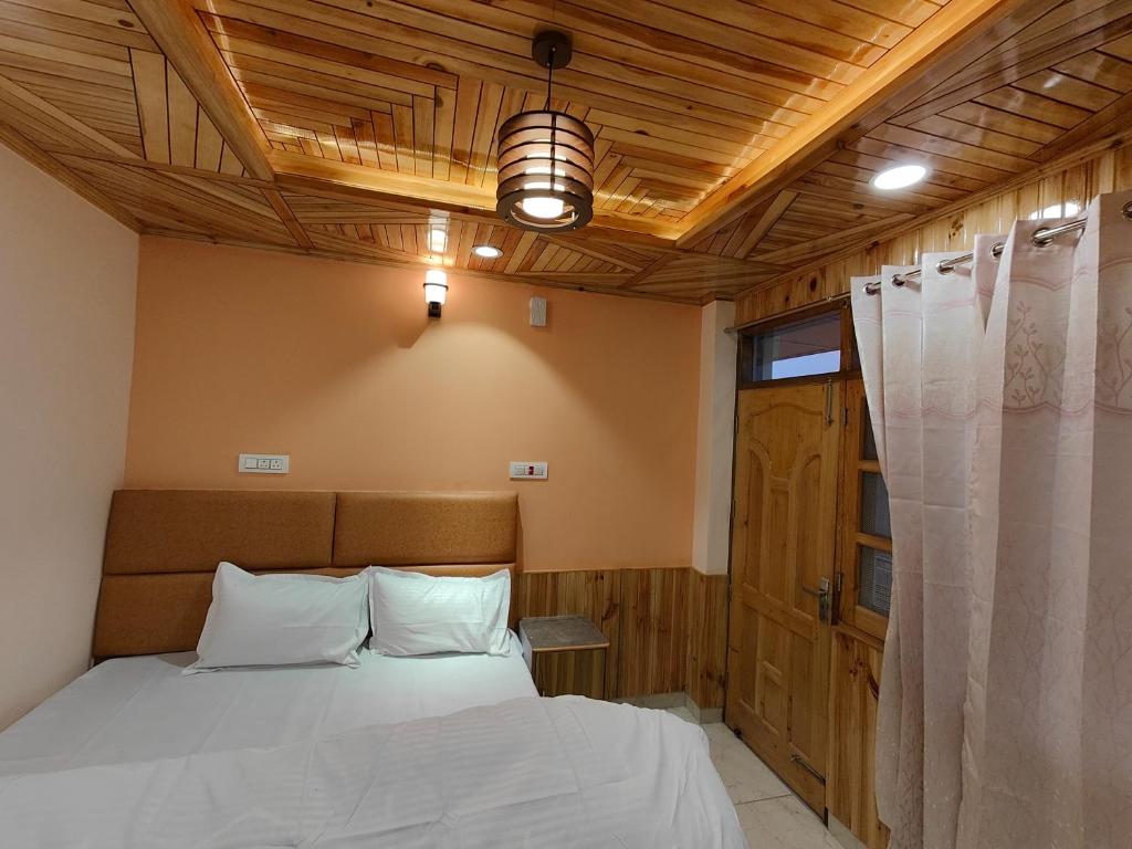 sypialnia z łóżkiem i drewnianym sufitem w obiekcie Alpine Valley Homestay w mieście Shimla