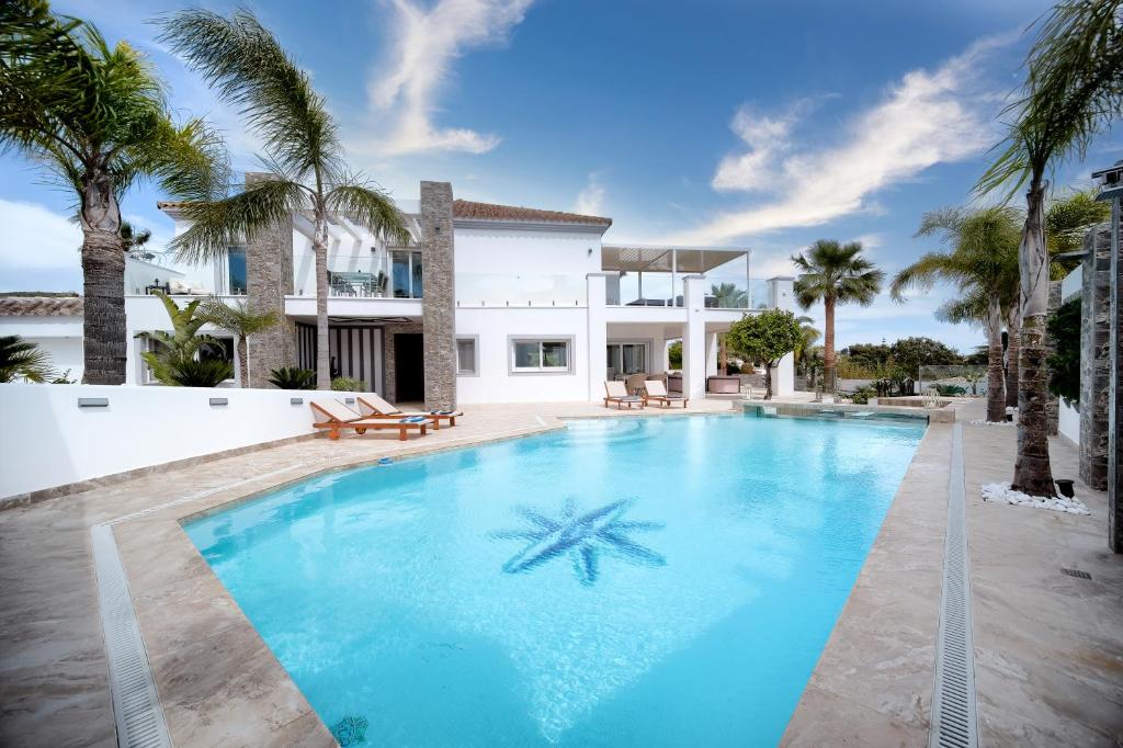 una piscina frente a una casa con palmeras en Villa Uno, en Sitio de Calahonda