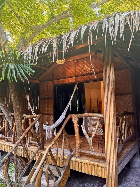 a wooden house with a hammock in front of it at Monkey Business Siquijor in Siquijor