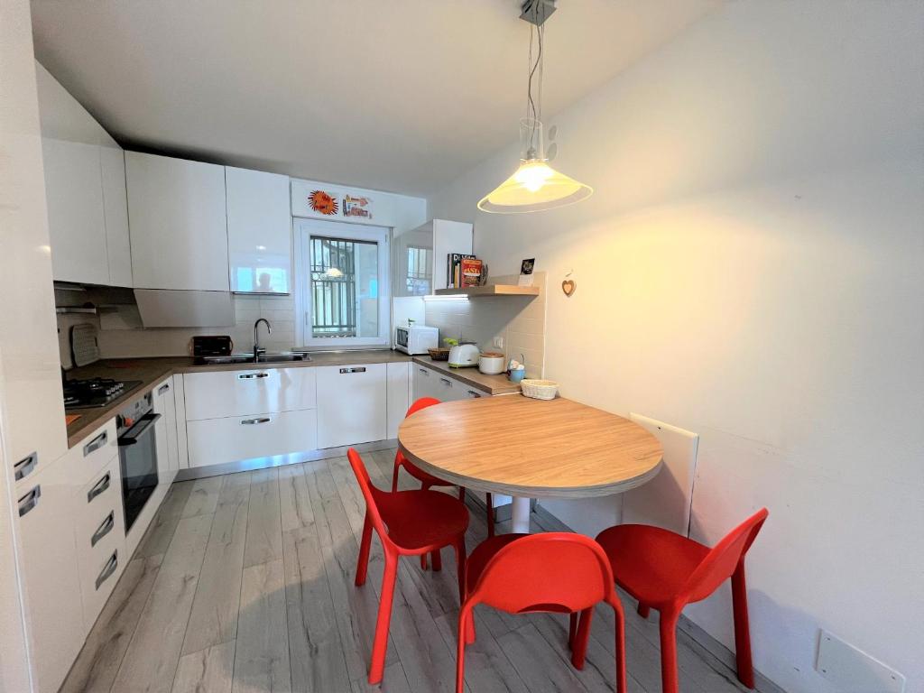 een keuken met een houten tafel en rode stoelen bij Nettuno in Grado