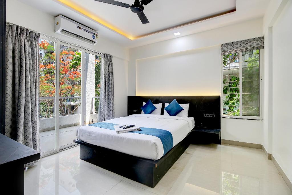 StayBird - Silver Oak, An Apartment Hotel, Kharadi في بيون: غرفة نوم مع سرير مزدوج كبير في غرفة مع نوافذ