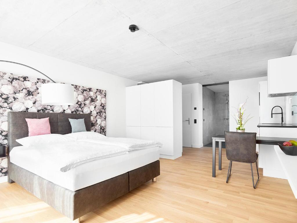 a white bedroom with a large bed and a desk at livisit bergapartments in Stuttgart