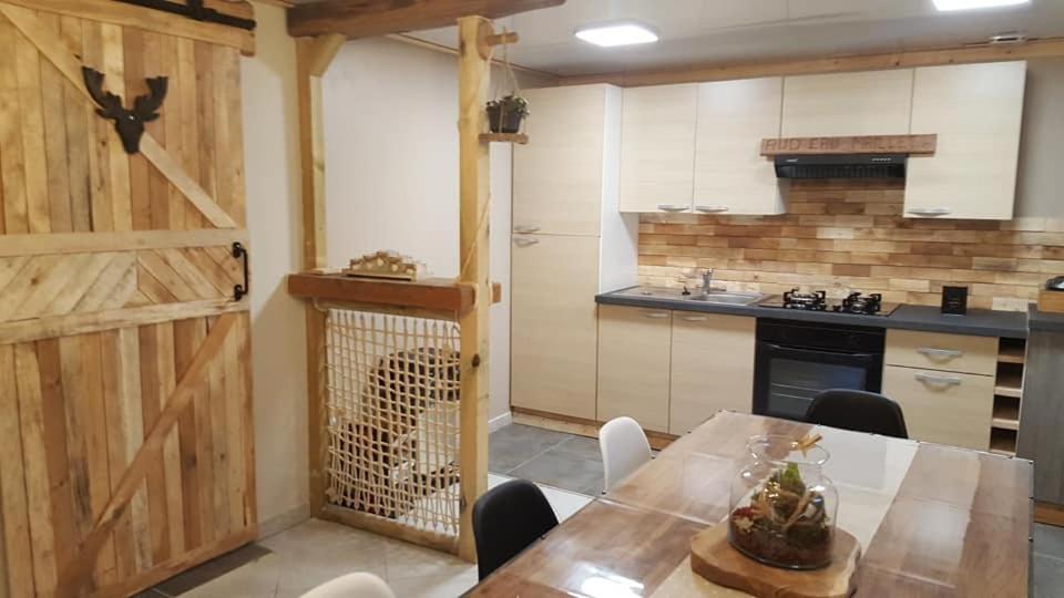 een keuken met een tafel en een houten schuurdeur bij aud eau maillet in Tilques
