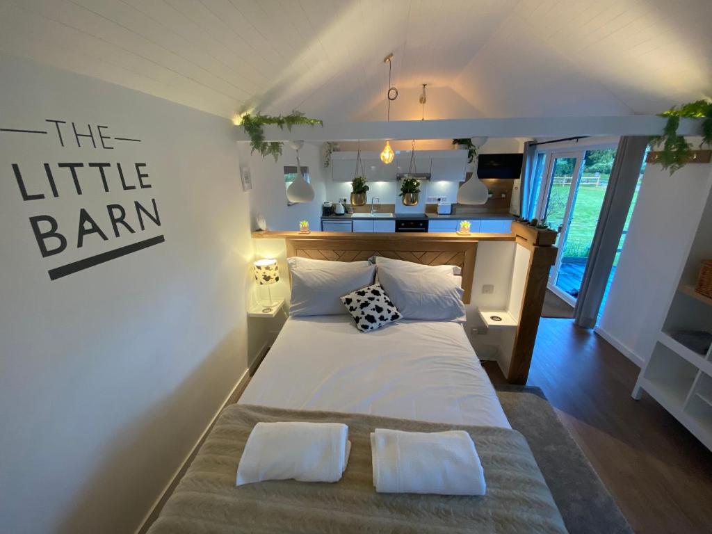 una camera da letto con un grande letto bianco con due cuscini di The Little Barn a Hoxne