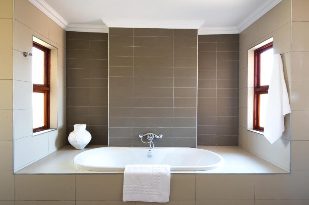 a bath tub in a bathroom with windows at The Finches Nest in Hammanskraal