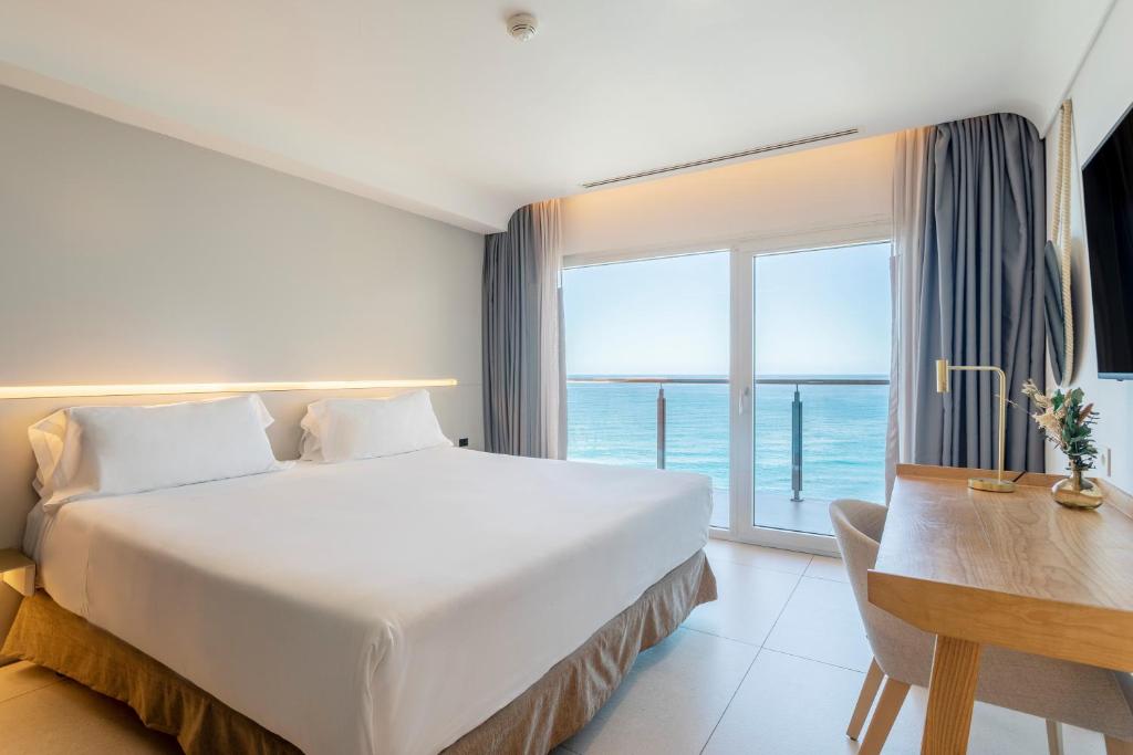 um quarto com uma cama, uma secretária e uma janela em Hotel Spa Porta Maris by Melia em Alicante