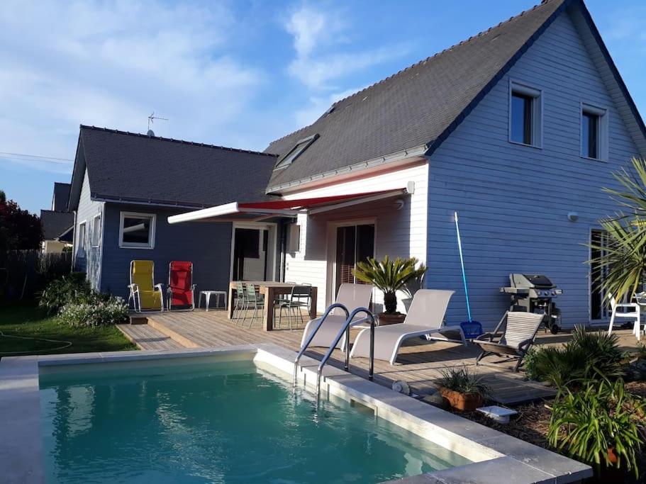 a house with a swimming pool in front of a house at Maison en bois avec piscine à 1000 m des plages. in Guidel