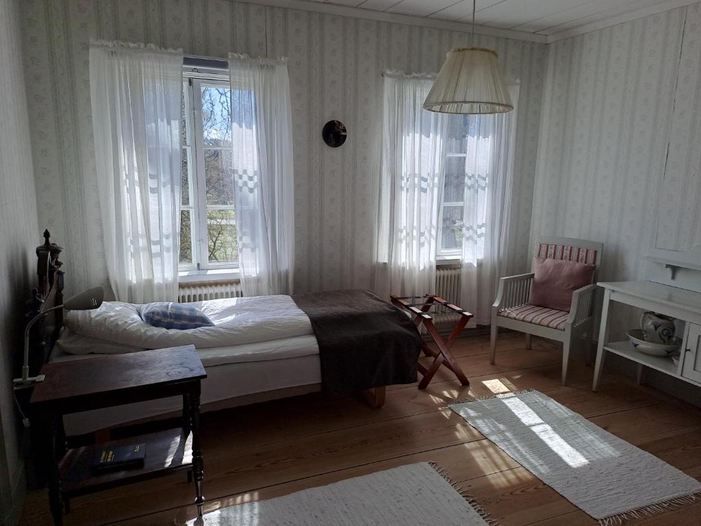 - une chambre avec un lit, une chaise et des fenêtres dans l'établissement Kristbergs Rusthåll, à Borensberg