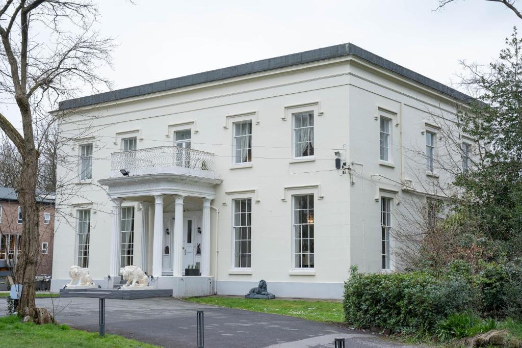 a white building with two statues in front of it at RainHill Hall Hotel in Rainhull