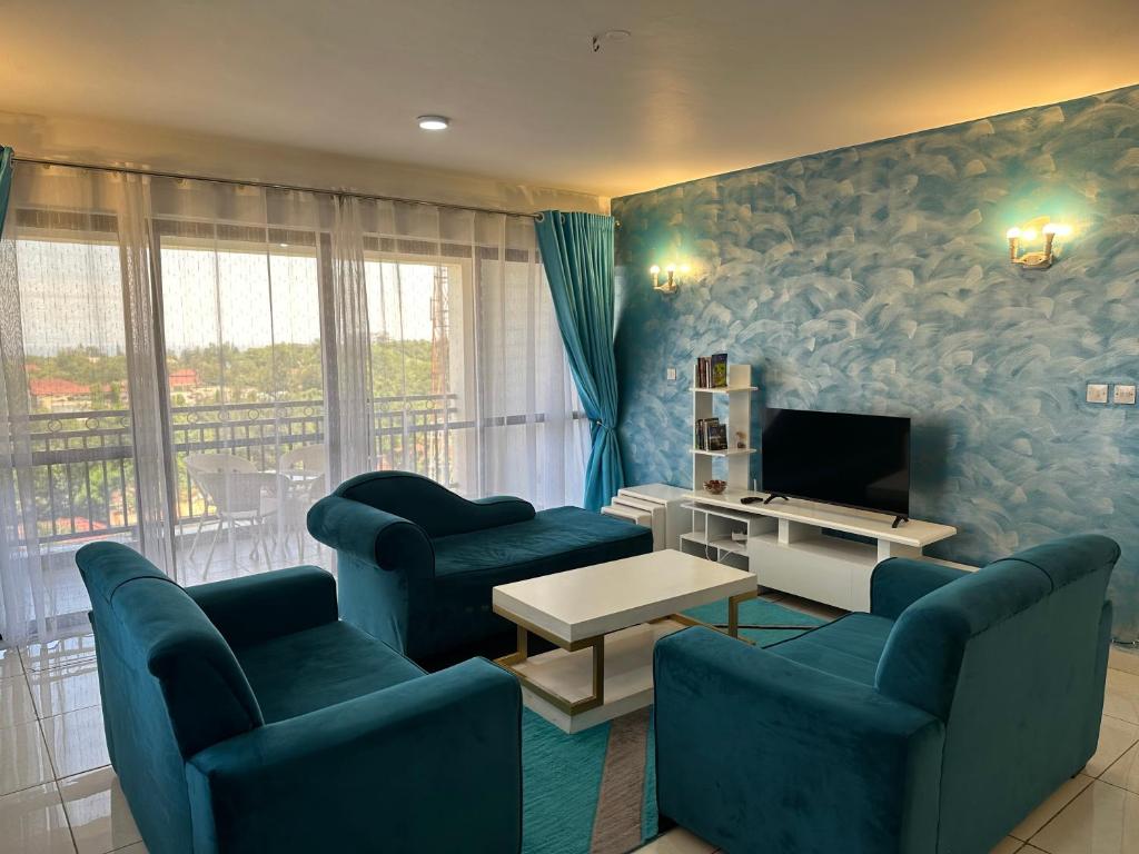 sala de estar con sofás azules y TV en Nyachaba Apartment, en Kisumu